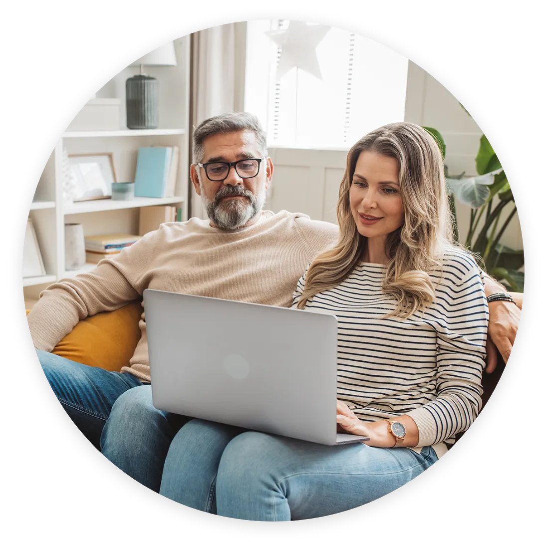 Man and woman smiling on couch looking at laptop